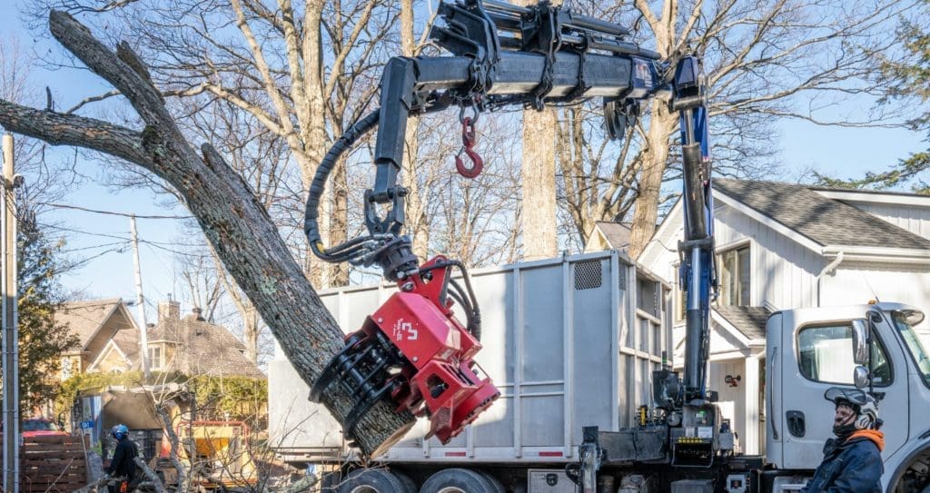 Arboriculteur utilisant une grue à bras articulé (knuckle boom) pour l’élagage d’arbres près de structures